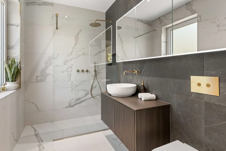 Walk-in shower room with marble-effect tiles and brushed brass fittings